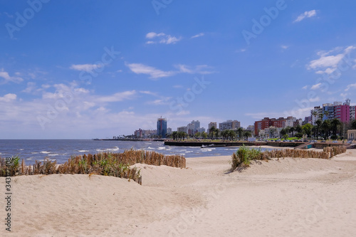 Montevideo beach with sand fence barriers and skyline on a sunny day, Montevideo, Uruguay photo