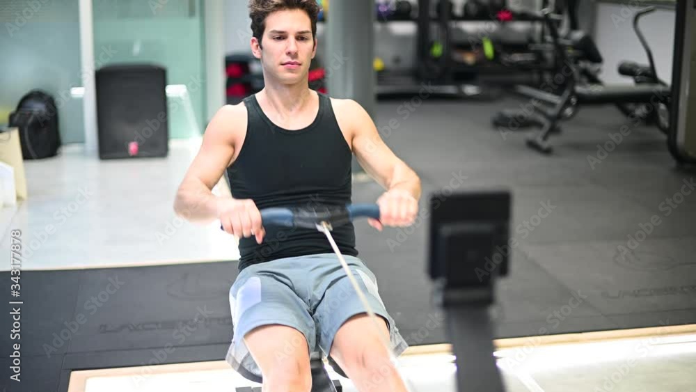 Young man working out on the rowing machine, training and fitness concept Young man working out on the rowing machine, training and fitness concept