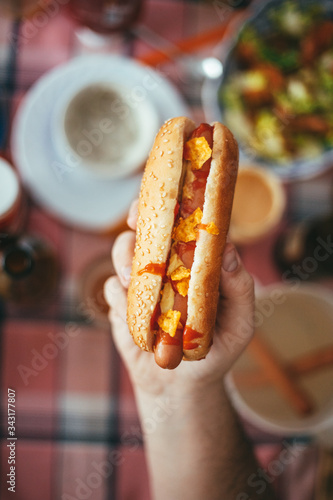 Hot dog in the hands of women on a table.
