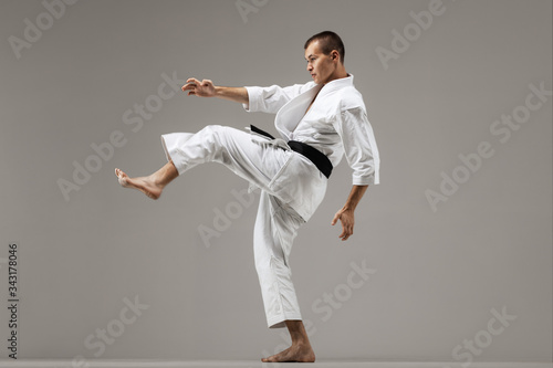 man exercising karate, against gray background