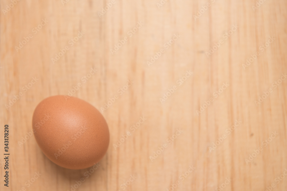 Close up of one chicken egg on a light brown wooden background, Top view with copy space Close up of one chicken egg on a light brown wooden background, Top view with copy space