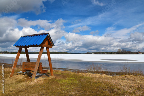 Swing on the shore of a frozen lake on a sunny spring day photo