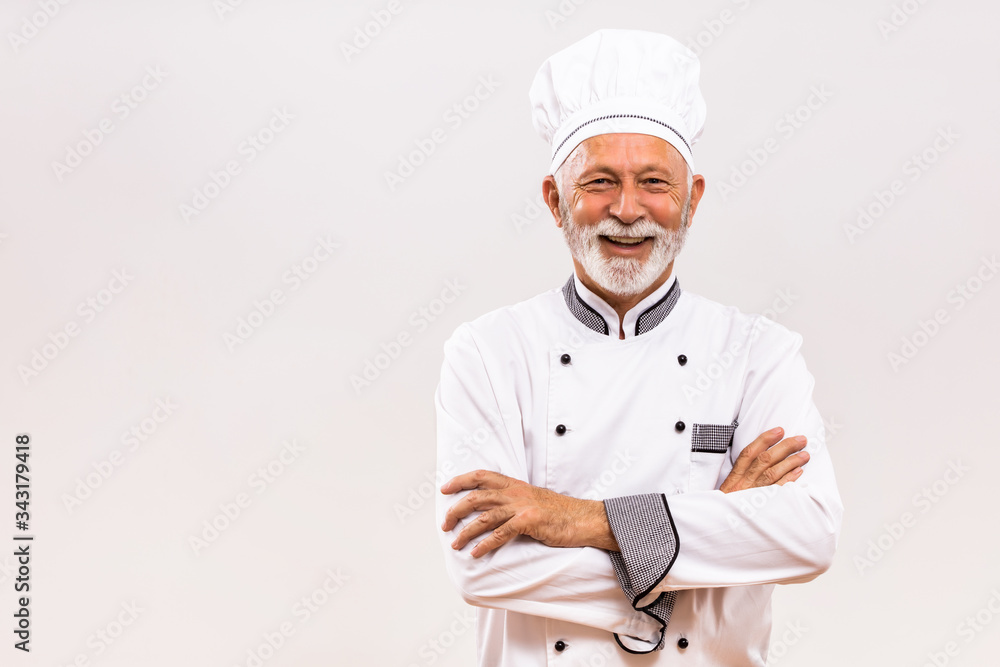 Portrait of senior chef  on gray background.