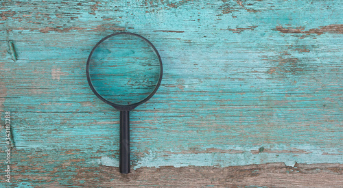 Plastic magnifier on aqua wooden background, top view copy space