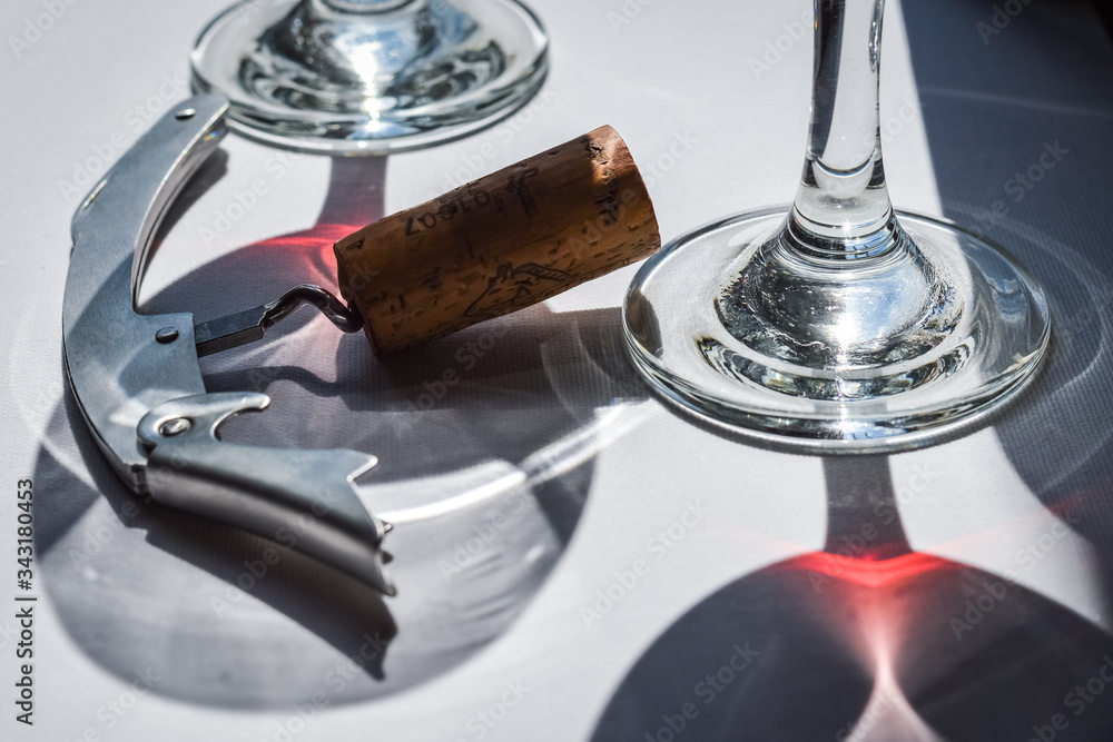 Closeup of glasses of red wine and bottle with shadows and reflections on a white textured surface. Closeup of glasses of red wine and bottle with shadows and reflections on a white textured surface.