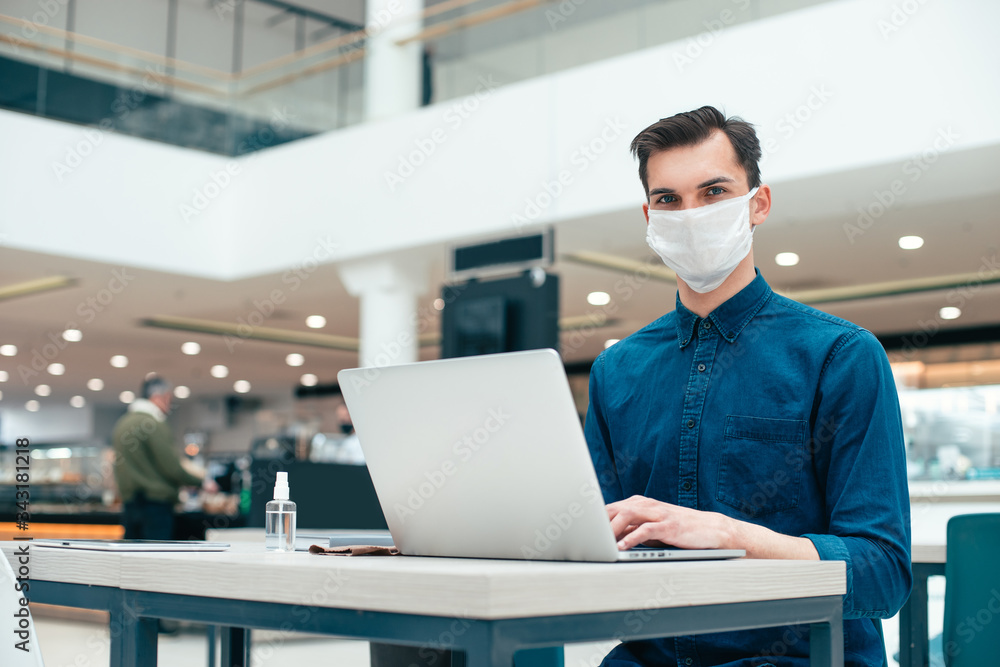 serious man in a protective mask sitting at an office Desk. serious man in a protective mask sitting at an office Desk.