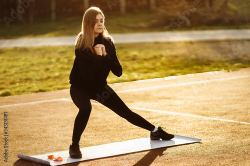 Fitness sport girl in fashion black sportswear doing yoga fitness exercise in the street.  © shunevich