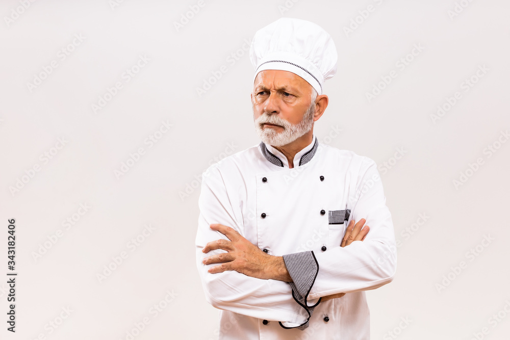 Portrait of angry senior chef  on gray background.