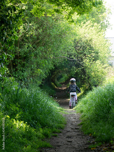 a child riding a small bike on a green forest path