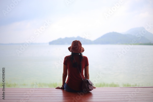A woman sitting and enjoying the view of the river and mountain