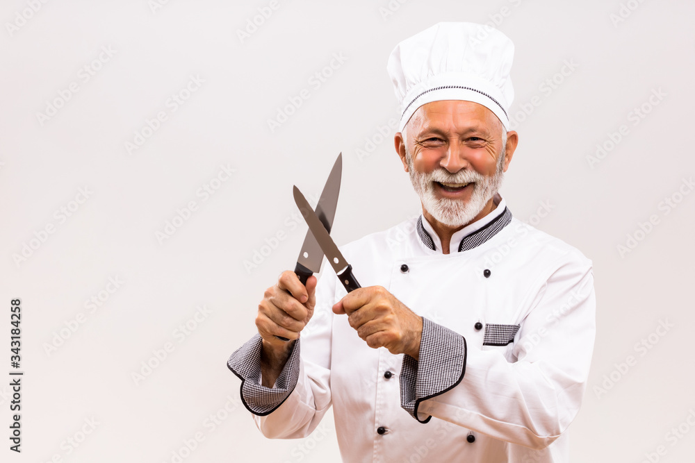 Image of happy chef sharpens knives on gray background. Image of happy chef sharpens knives on gray background.