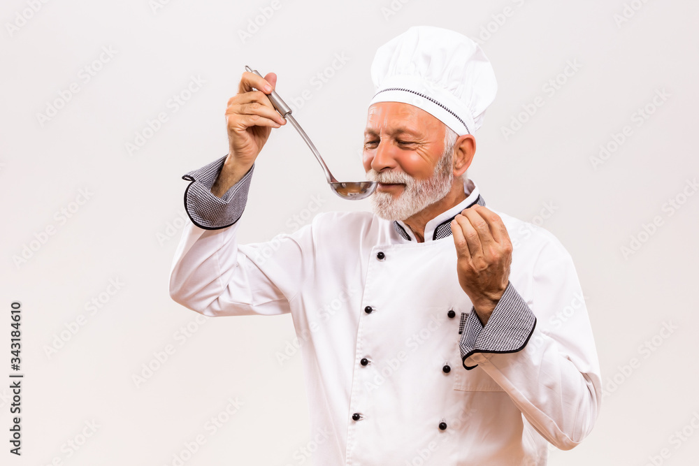 Portrait of content senior chef tasting soup. Portrait of content senior chef tasting soup.