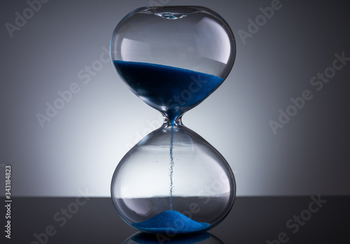 Blue sand hourglass on black background 