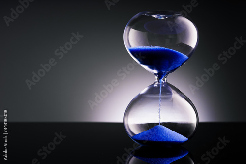 Blue sand hourglass on black background