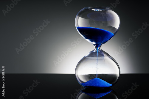 Blue sand hourglass on black background 