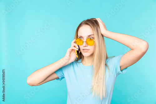 Wallpaper Mural Image of a young woman holding smartphone and expressing amazement isolated over blue background. Torontodigital.ca