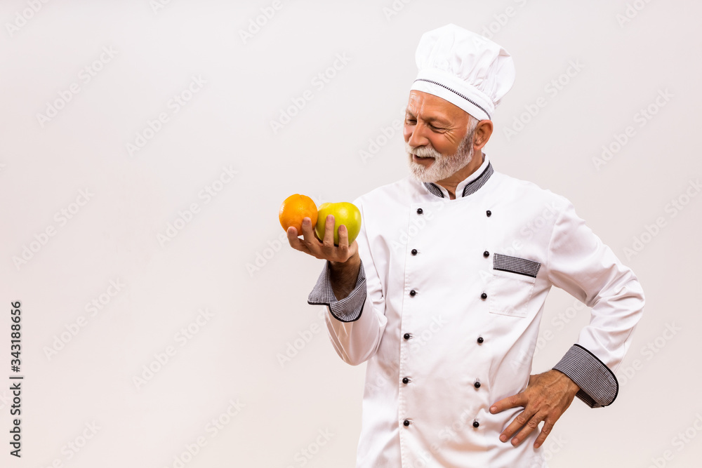 Image of senior chef holding fruit and thinking on gray background. Image of senior chef holding fruit and thinking on gray background.