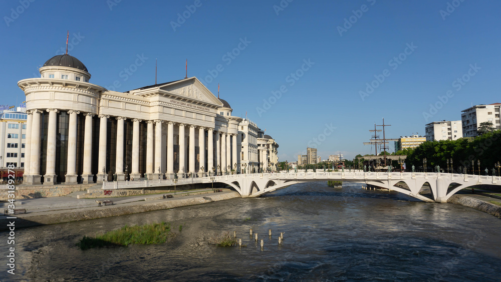 Skopje, North Macedonia, June 7 2019: View of Archaeological Museum of Macedonia and stone bridge with river in downtown of Skopje blue sky in the background on summer day.