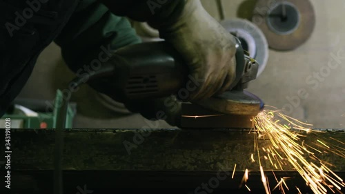 worker with grinder works steel with sparks in the camera in slow motion