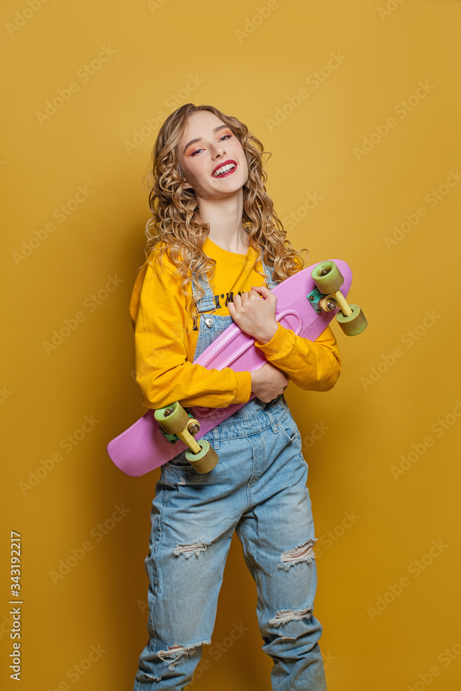 Excited woman with skateboard on bright yellow background. Positive emotion Excited woman with skateboard on bright yellow background. Positive emotion