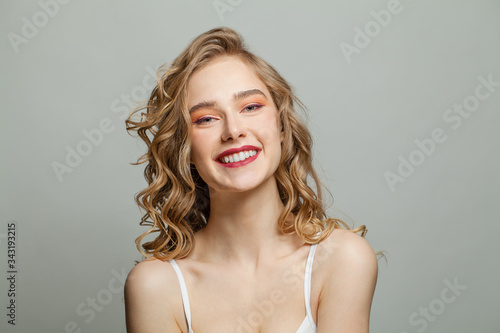 Happy woman with long blonde curly hair on white background