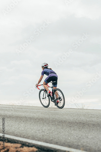Isolated female road cyclist cycling up the hill