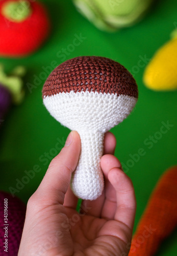 photo knitted toy mushroom in hand on a green background