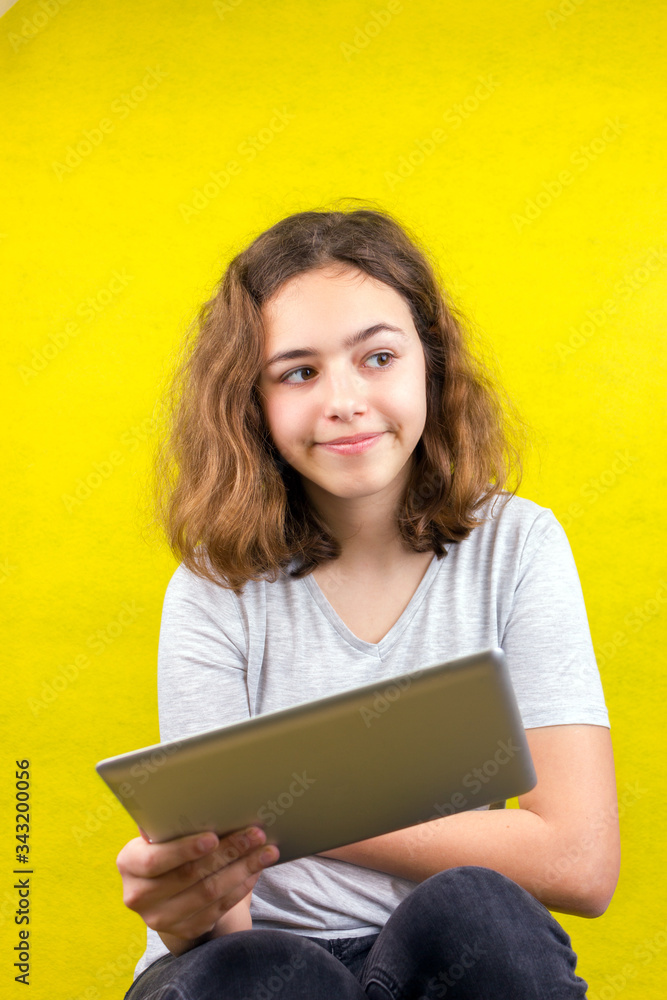 Curly beautiful girl watching video on tablet. Online lessons. Home education. Quarantine and isolation. Curly beautiful girl watching video on tablet. Online lessons. Home education. Quarantine and isolation.