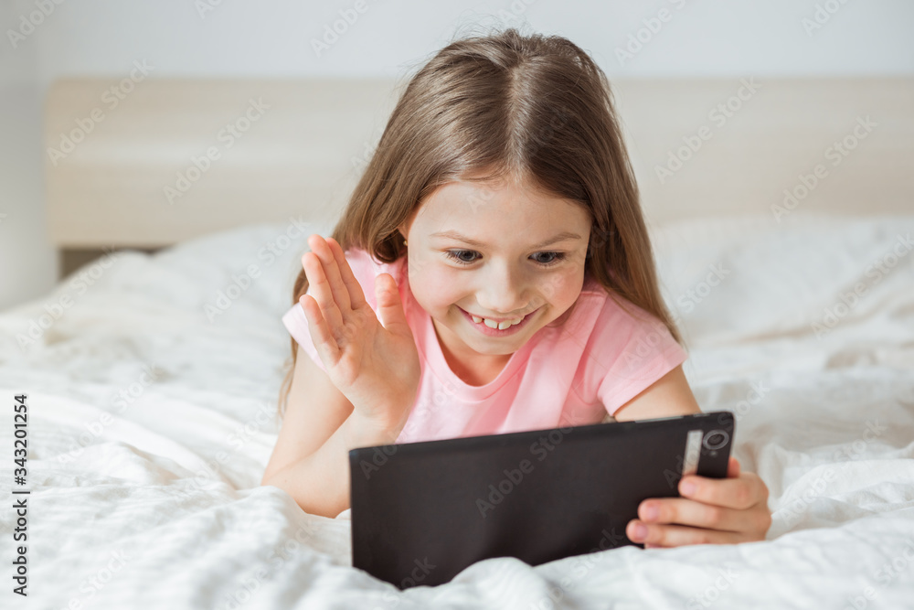 Attractive young teenager lying on the bed smiling and looking to laptop chatting with friends. Online surfing, messaging or working from home theme Attractive young teenager lying on the bed smiling and looking to laptop chatting with friends. Online surfing, messaging or working from home theme