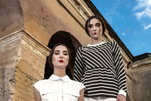 Outdoor fashion portrait of two young beautiful women wearing fashionable clothes posing on the street © Natallia