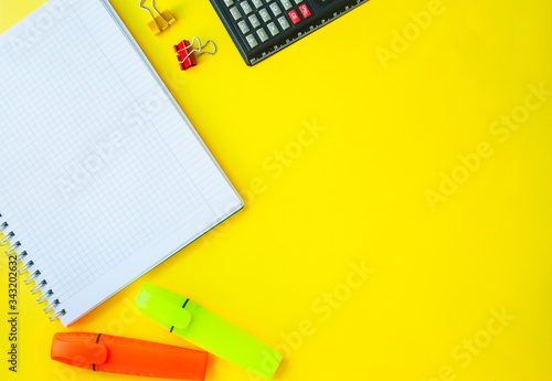 open notebook in a ruler on a yellow background. next to office supplies. business concept for a girl or back to school
