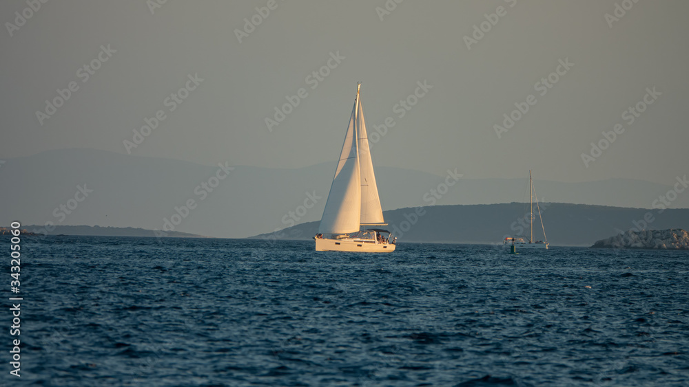 Sailing boat at sea, side view. Yacht is sailing in the Adriatic Sea against the backdrop of forested islands, Croatia.