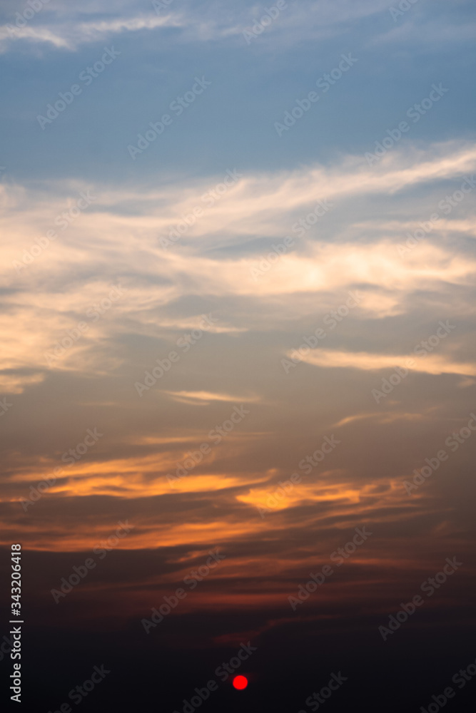 Beautiful orange sunset or sunrise with clouds. Colorful dramatic sky. Twilight bright sky background. Vertical shot. 