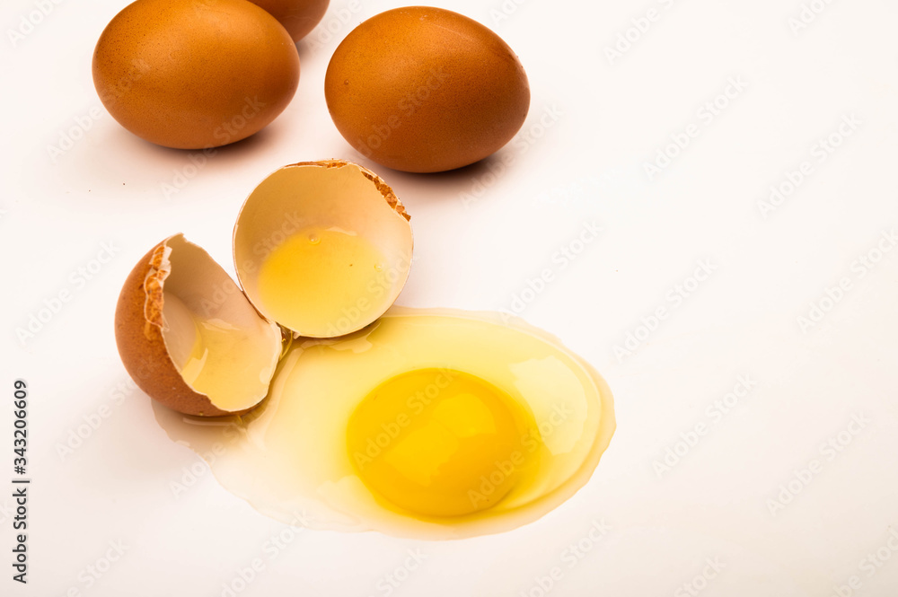 A broken chicken egg and scattered eggs on a white background. Close up. A broken chicken egg and scattered eggs on a white background. Close up.