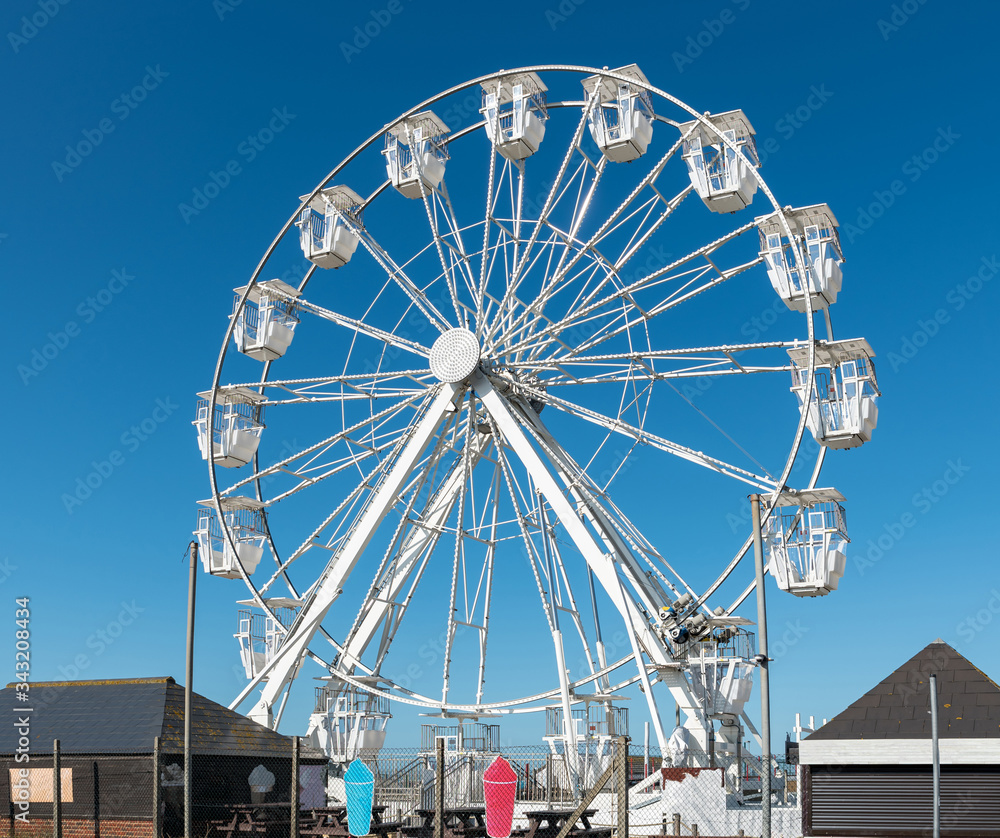 White Ferris wheel in Hastings on blue background.