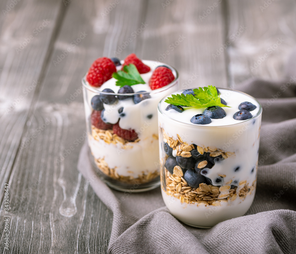 White yogurt in glass jar with fruits on grey background. White yogurt in glass jar with fruits on grey background.