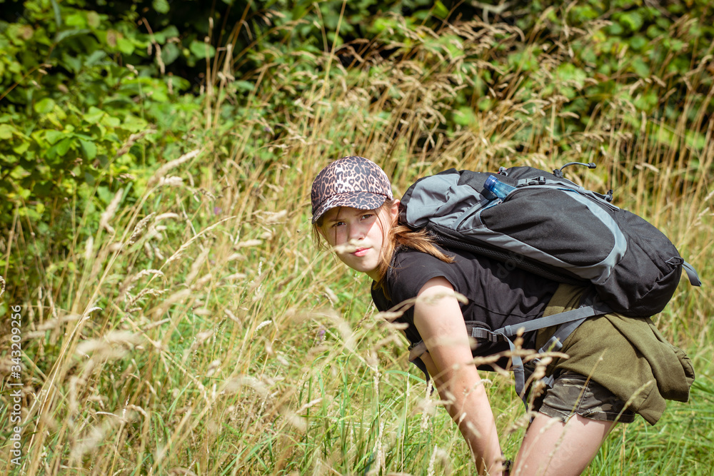 Teenage girl exploring nature on a long hike in the countryshide with backpack