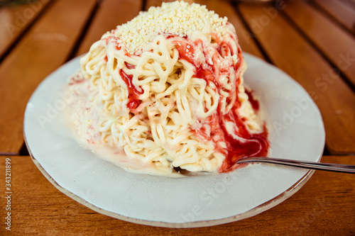 A serving of the German novelty food spaghettieis - vanilla ice-cream and strawberry suace as an illusion of spaghetti