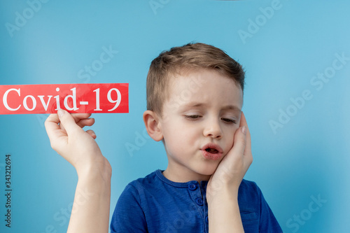 Little boy pointing to red paper with mesaage Coronavirus on blue background. World Health Organization WHO introduced new official name for Coronavirus disease named COVID-19 photo