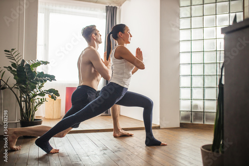 young caucasian married couple keep balance in yoga pose, stand with one leg in back