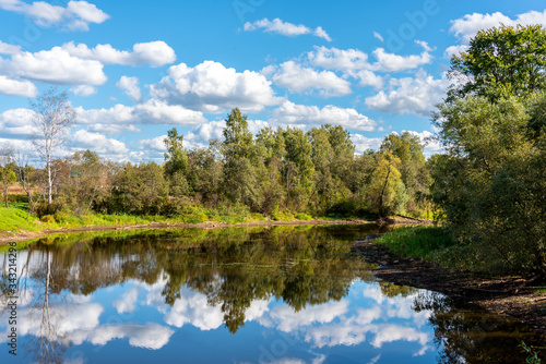 Rural landscape with a small forest river and reflection in the water