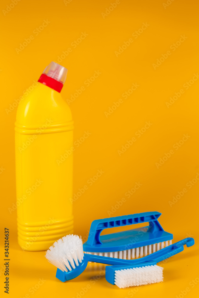 Bottle with detergent powder and brushes on yellow background, space for text. Bottle with detergent powder and brushes on yellow background, space for text.