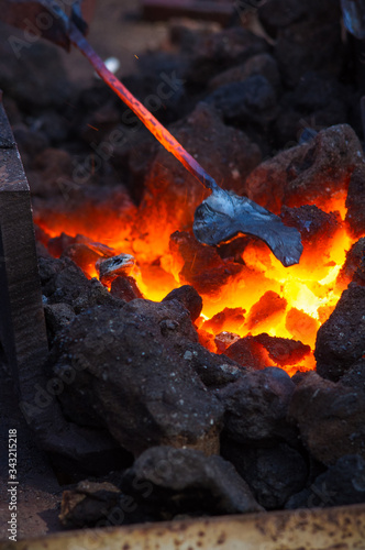 blacksmith furnace with burning coals, tools, and glowing hot metal workpieces