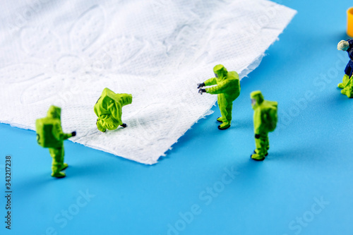 a team of miniature figurines checking a cleanliness of toilet paper as a symbol of hygiene preventive measurment photo
