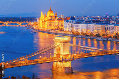 Budapest, Hungary. Night view on Parliament building and Chain Bridge over delta of Danube river. Picturesque view of illuminated night European capital city.