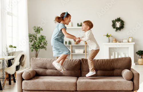 Happy siblings jumping on sofa.