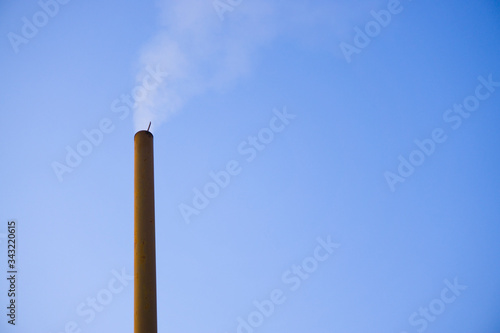 Steaming chimney smoke on isolated blue sky outdoor background. Climate change, environmental issue concept.