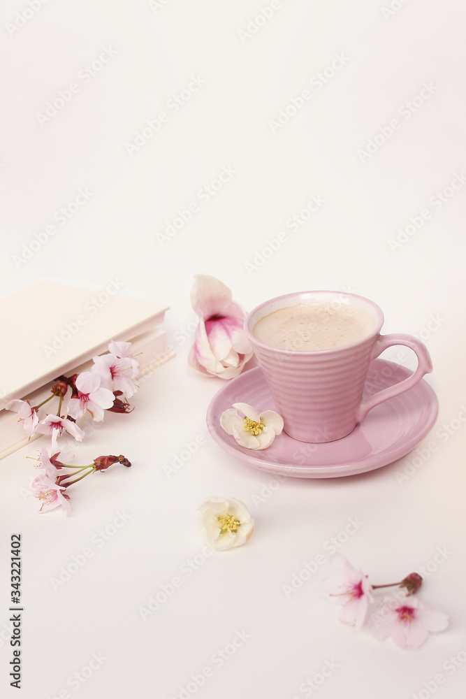 cup of cappuccino on a white table, blooming magnolia buds, a book in a white cover on a delicate pink background, a blank for the designer, an invitation form, a spring mood concept cup of cappuccino on a white table, blooming magnolia buds, a book in a white cover on a delicate pink background, a blank for the designer, an invitation form, a spring mood concept