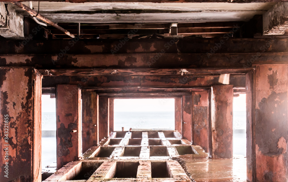 Diminishing perspective of pillars underneath long old pier standing in sea water at sunset