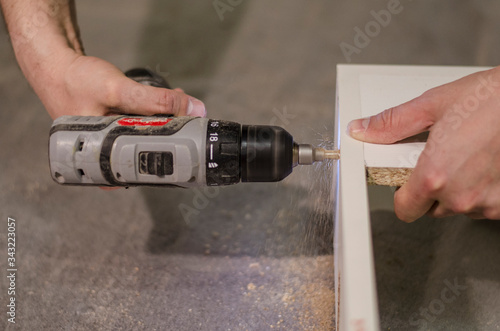 Worker's hands holding a drill making holes on a body plane 